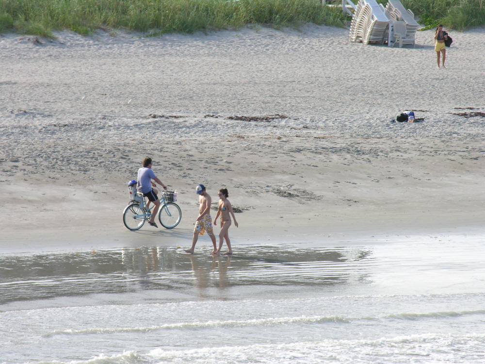 Riding bicycle down the beach with baby in bike seat, Cocoa Beach Florida