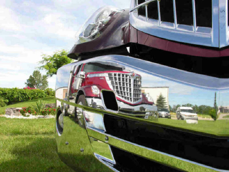 Reflection of a new red International Lonestar in the bumper of a new red International Lonestar