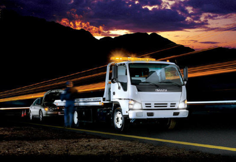 Isuzu tow truck helping disabled motorist on the side of the road