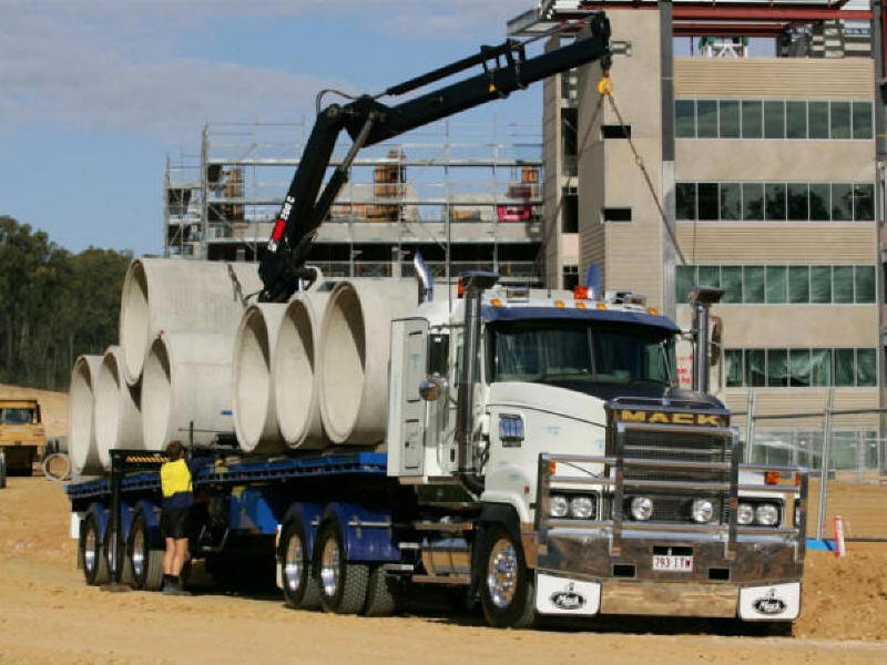 Photo of Mack Truck carrying concrete sewer pipes on blue flatbed trailer